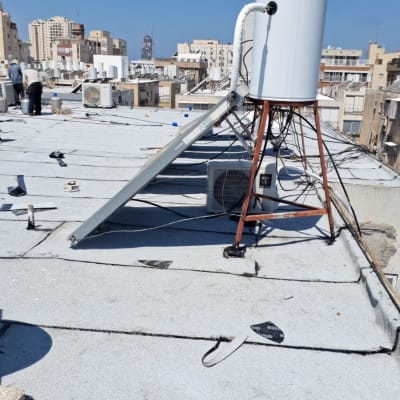 גג עם יריעות איטום, דודי שמש וצינורות.