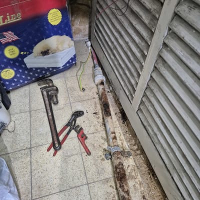 כלי עבודה של אינסטלטור ליד צינור חלוד על הרצפה