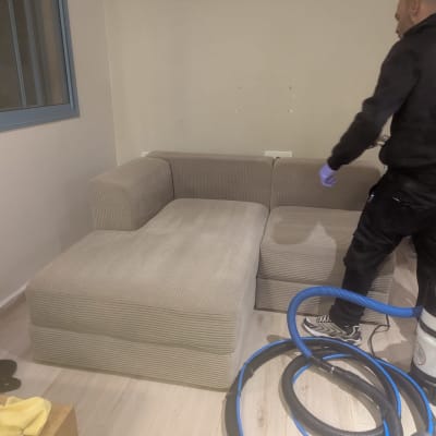 ניקוי ספה עם ציוד מקצועי ואדם בעבודה