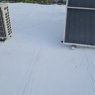 גג אטום עם חומר לבן ליד מזגן וקולטים