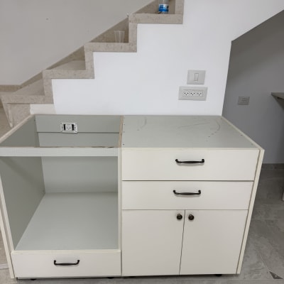 ארון מטבח לבן עם מגירות ודלתות ליד גרם מדרגות