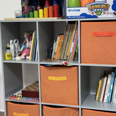 מדפים עם צעצועים, ספרים וקופסאות אחסון כתומות