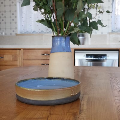 אגרטל קרמיקה עם פרחים על שולחן עץ במטבח