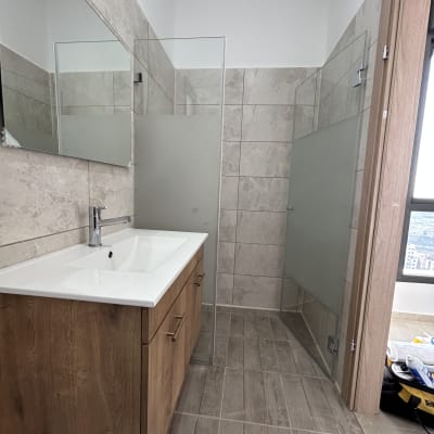 מקלחון זכוכית עם דלת חלבית ורצפת אריחים