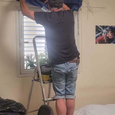 אדם על סולם מתקין כיסוי למזגן