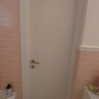 דלת לבנה עם ידית מתכת בחדר אמבטיה