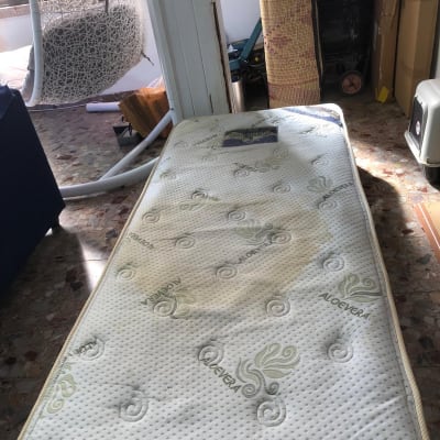 מזרן עם כתם על הרצפה ליד כיסא תלוי