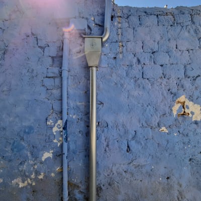 צינור מרזב מותקן על קיר לבנים כחול