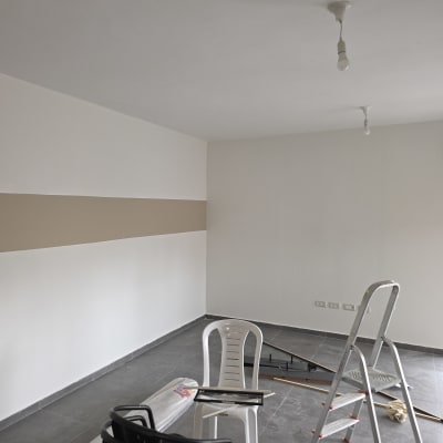 חדר צבוע עם סולם וכיסאות, קיר בצבעים שונים