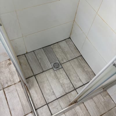 מקלחת עם רצפת אריחים ודלת זכוכית