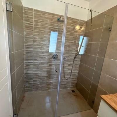 מקלחון זכוכית עם אריחים חומים וראש מקלחת