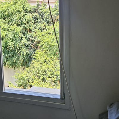 חלון פתוח עם נוף של עצים וגג רעפים