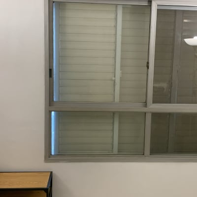 חלון זכוכית עם תריסים וצמחים על מדף