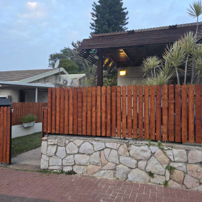 גדר עץ חומה עם צמחים מסביב לבית