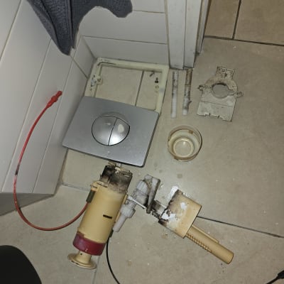 חלקי אסלה מפורקים על רצפת חדר אמבטיה