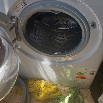 מכונת כביסה פתוחה עם בגדים על הרצפה