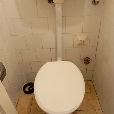 אסלה עם צינור מים וכתמי רטיבות על הקיר