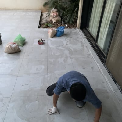 אדם משפשף רצפה עם כפפות, שקי חומרי בנייה