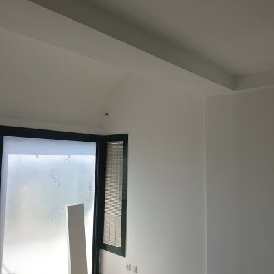 קיר צבוע בלבן עם חלון גדול ותריסים