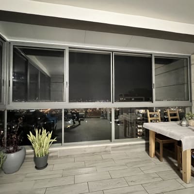 חלונות אלומיניום גדולים במרפסת סגורה בלילה