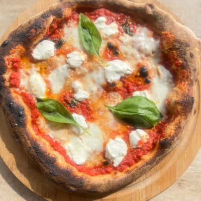 פיצה מרגריטה עם עלי בזיליקום על קרש עץ