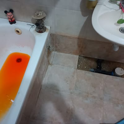 אמבטיה עם מים כתומים, צינור חשוף ברצפה
