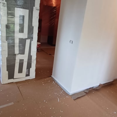 דירה בתהליך צביעה עם קירות לבנים ורצפה מוגנת בקרטונים