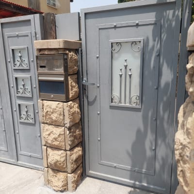 שער מתכת אפור עם עיטורים ודלת זכוכית.