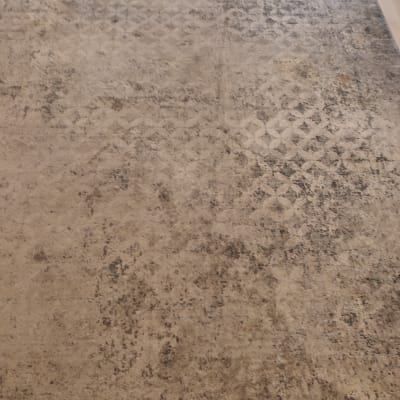 שטיח עם כתמים כהים על רצפה בהירה