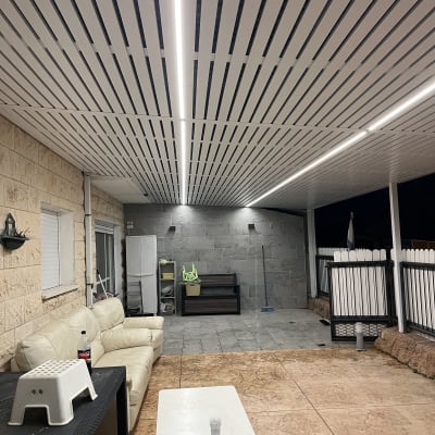 פרגולה מאלומיניום עם תאורה מעל מרפסת מרוהטת