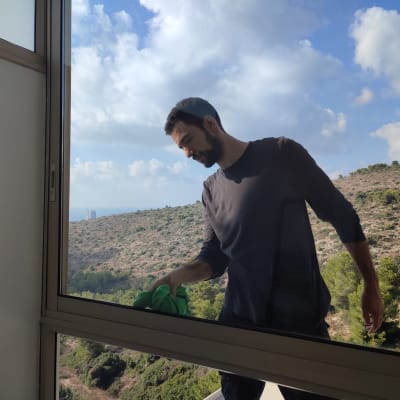 אדם מנקה חלון עם מטלית ירוקה