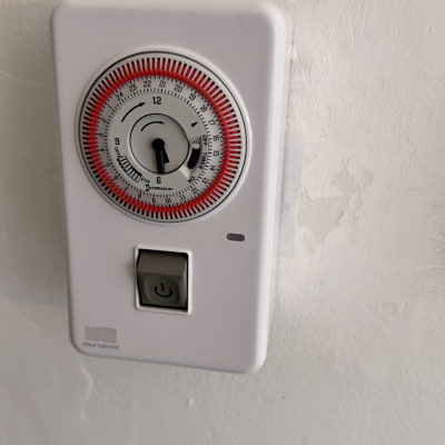 טיימר חשמלי עם כפתור הפעלה על קיר לבן