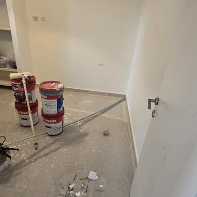 דלי צבע ומברשת על רצפה בחדר ריק