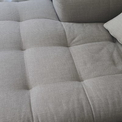 ספה אפורה עם כרית על רקע וילון לבן