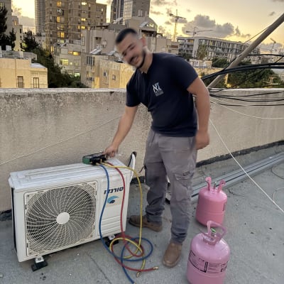 אדם עובד על מזגן על גג עם בלוני גז