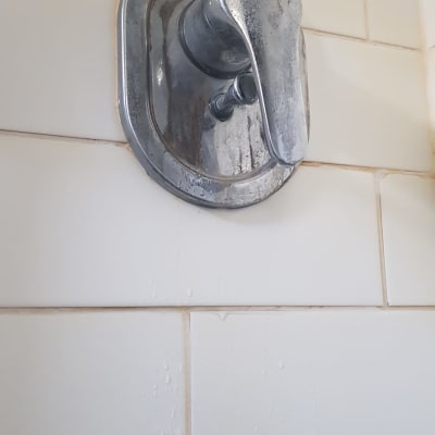 ברז מים מתכתי על קיר אריחים לבנים