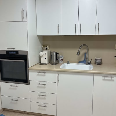 מטבח עם ארונות לבנים, כיור וברז, קומקום חשמלי