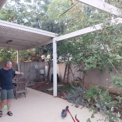 אדם עומד ליד גינה עם עצים וכלי גינון