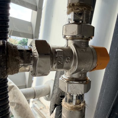 שסתום מתכת עם ידית כתומה בצנרת