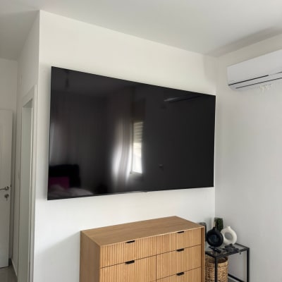 טלוויזיה מותקנת על קיר מעל שידה בחדר