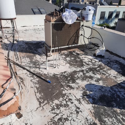 גג עם סדקים ואיטום מתקלף סביב צינורות ומזגן