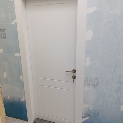 דלת לבנה עם ידית כסופה על רקע קיר כחול