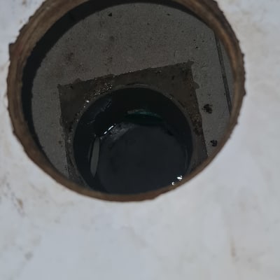 מבט לתוך פתח ניקוז וקופסת ביקורת ברצפה עם מים עומדים