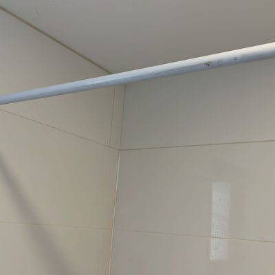 מוט תלייה לבן מותקן על קיר אריחים