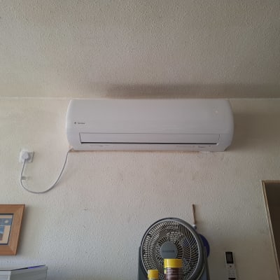 מזגן מותקן על קיר עם מאוורר ושלט רחוק