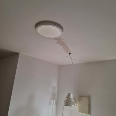 תקרה עם חוטי חשמל חשופים ליד מנורה