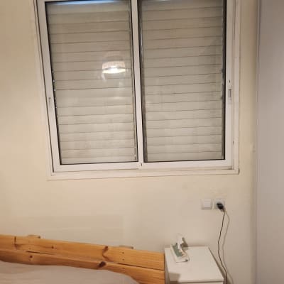 חלון אלומיניום עם תריסים סגורים על קיר לבן