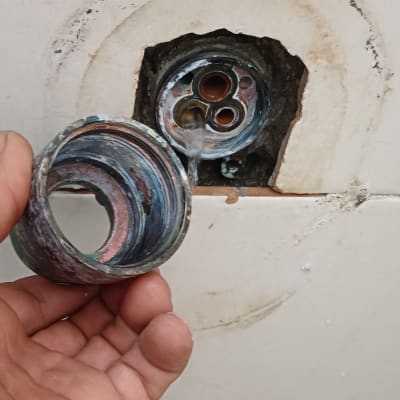 יד מחזיקה חלק צנרת מתכת עם חור בקיר