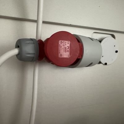 תקע תעשייתי אדום מחובר לשקע על קיר