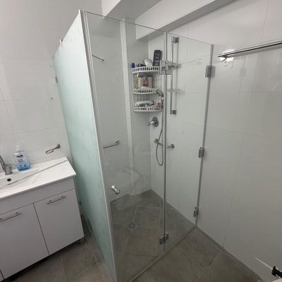 מקלחון פינתי מזכוכית עם דלתות ציר בחדר רחצה